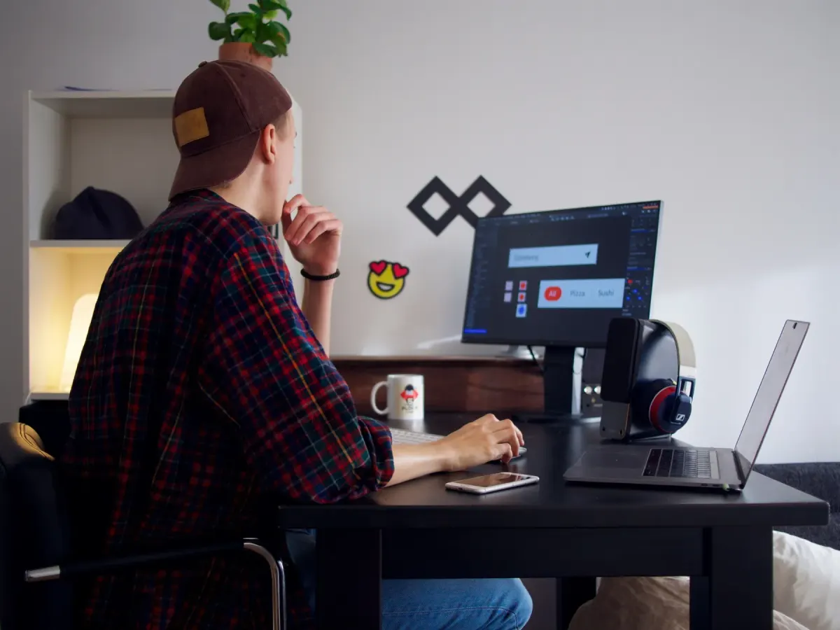 Um designer a trabalhar na interface de uma aplicação num monitor de secretária, num pequeno escritório em casa