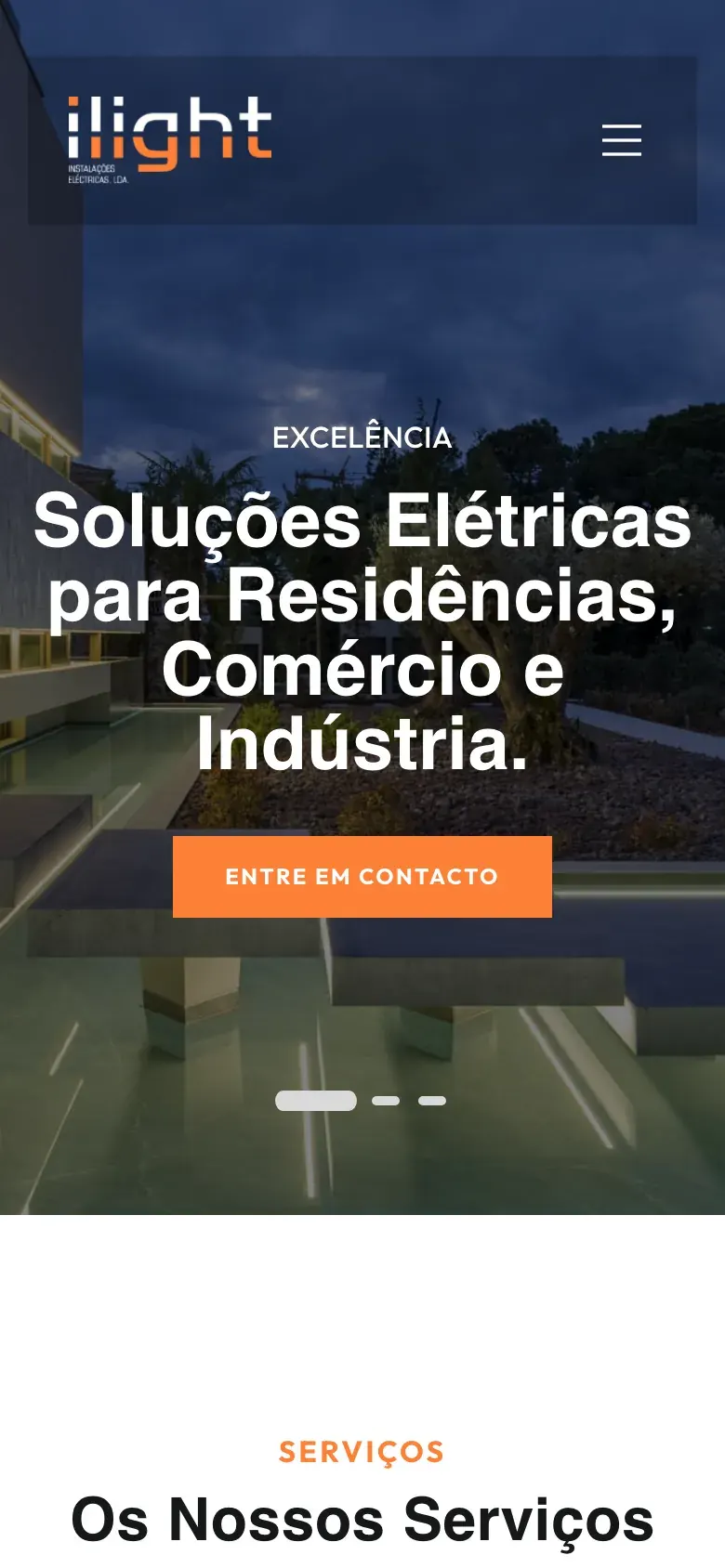 Página inicial da ILIGHT com uma casa moderna iluminada ao anoitecer e o título "Soluções Elétricas para Residências, Comércio e Indústria", num telemóvel